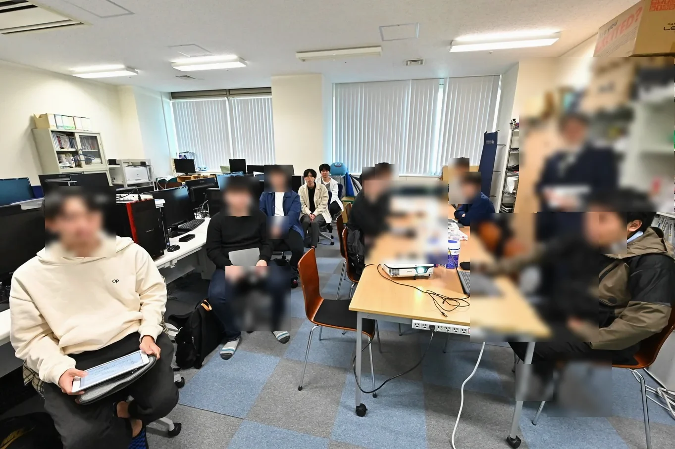 学生が机を囲み、ゼミで議論している研究室の様子(顔をぼかし加工)